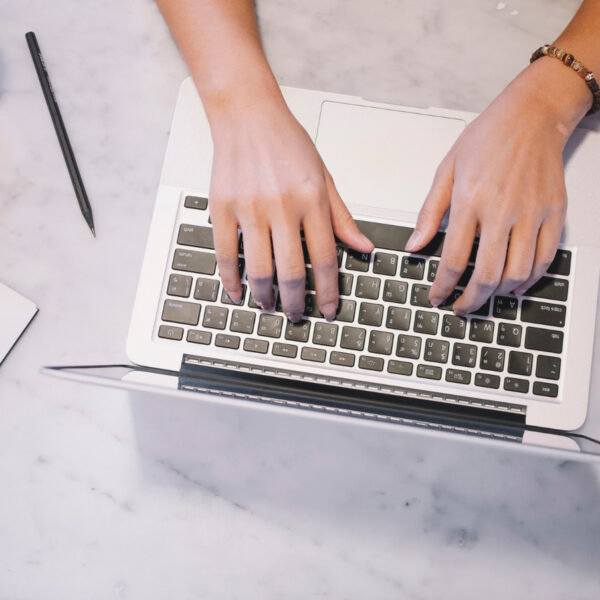 Des mains rédigent un post sur un clavier d'ordinateur